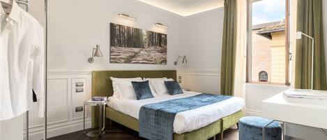 A modern bedroom with a green upholstered bed, a side table, a large window with curtains, and a painting above the bed.