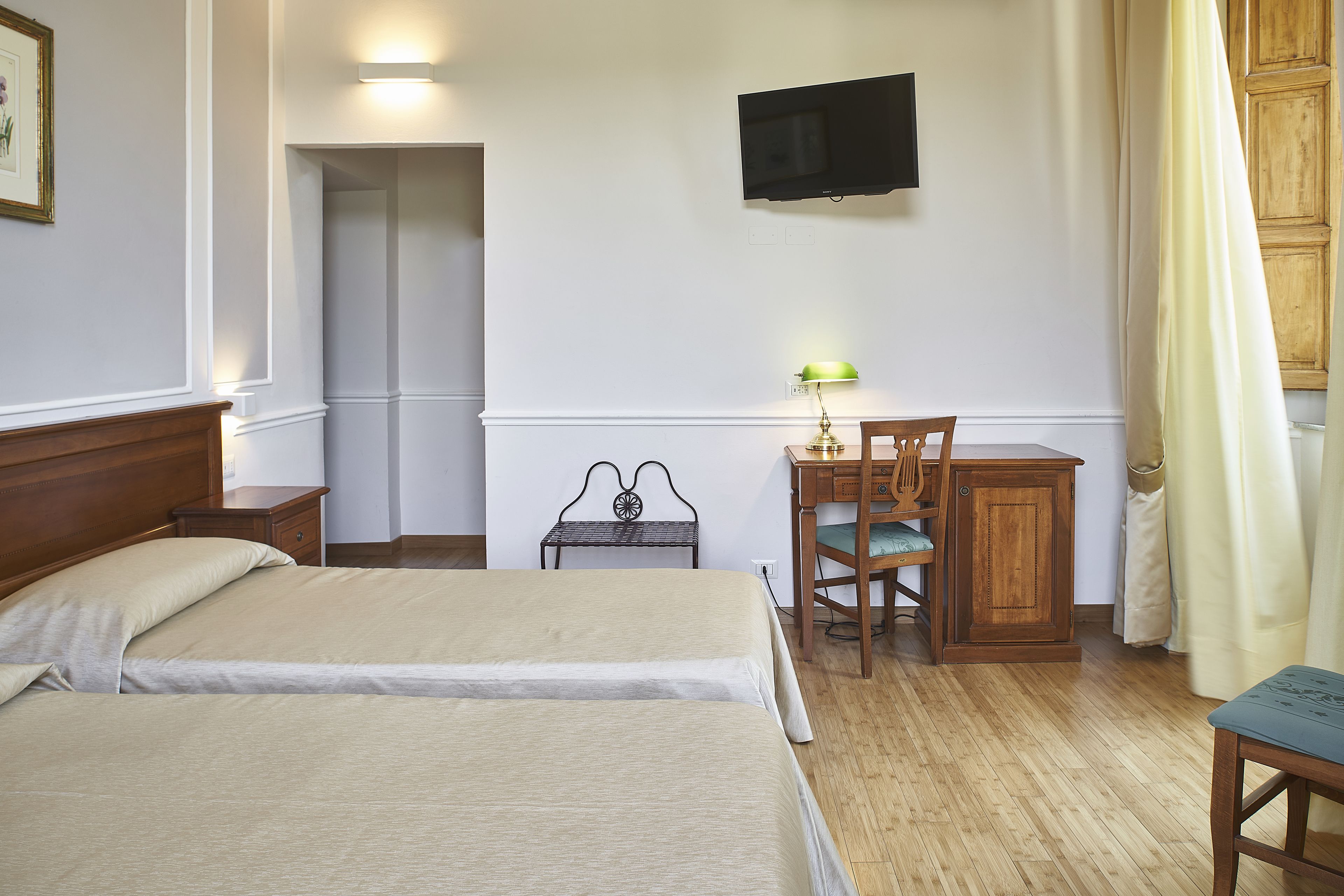 A hotel room with two beds, a desk with a chair, a television, and a small table.