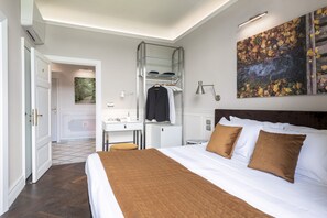 Habitación de hotel con una cama grande, un escritorio con una silla, un armario y un cuadro en la pared.