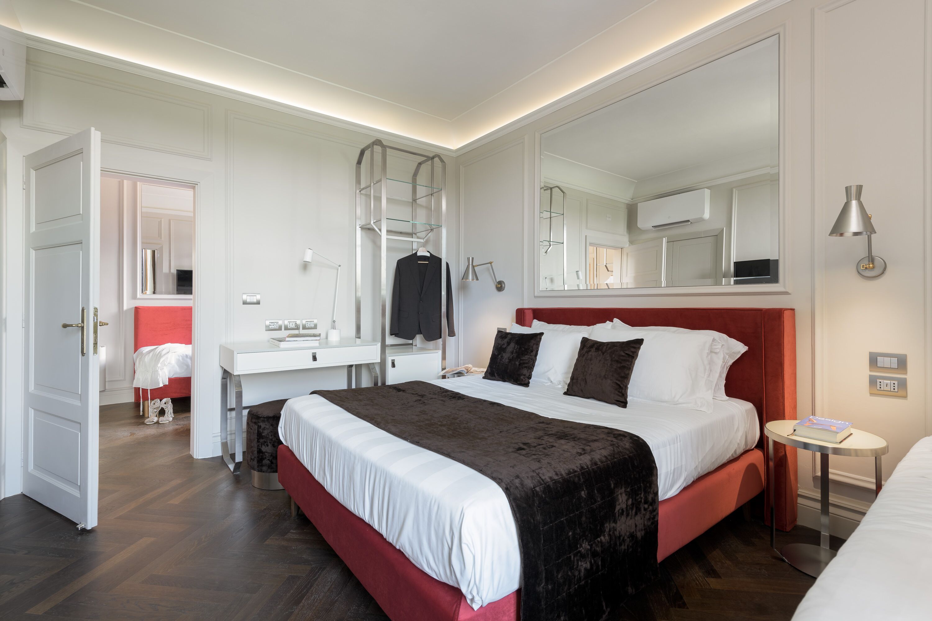Ein modernes Hotelzimmer mit einem großen Bett, einem Nachttisch, einem Spiegel und einem Kleiderschrank.