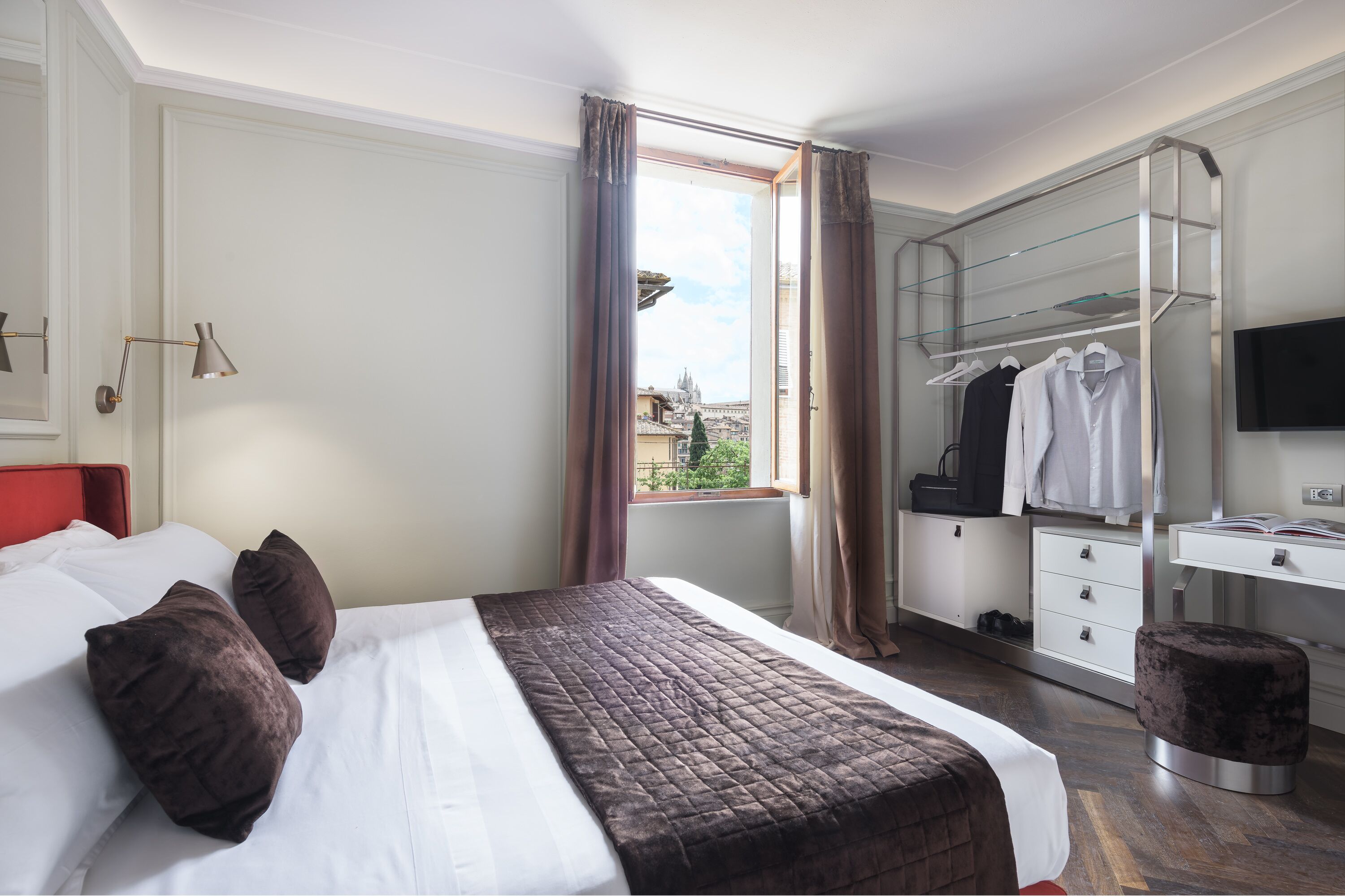 A hotel room with a bed, a wardrobe, a desk, and a television.