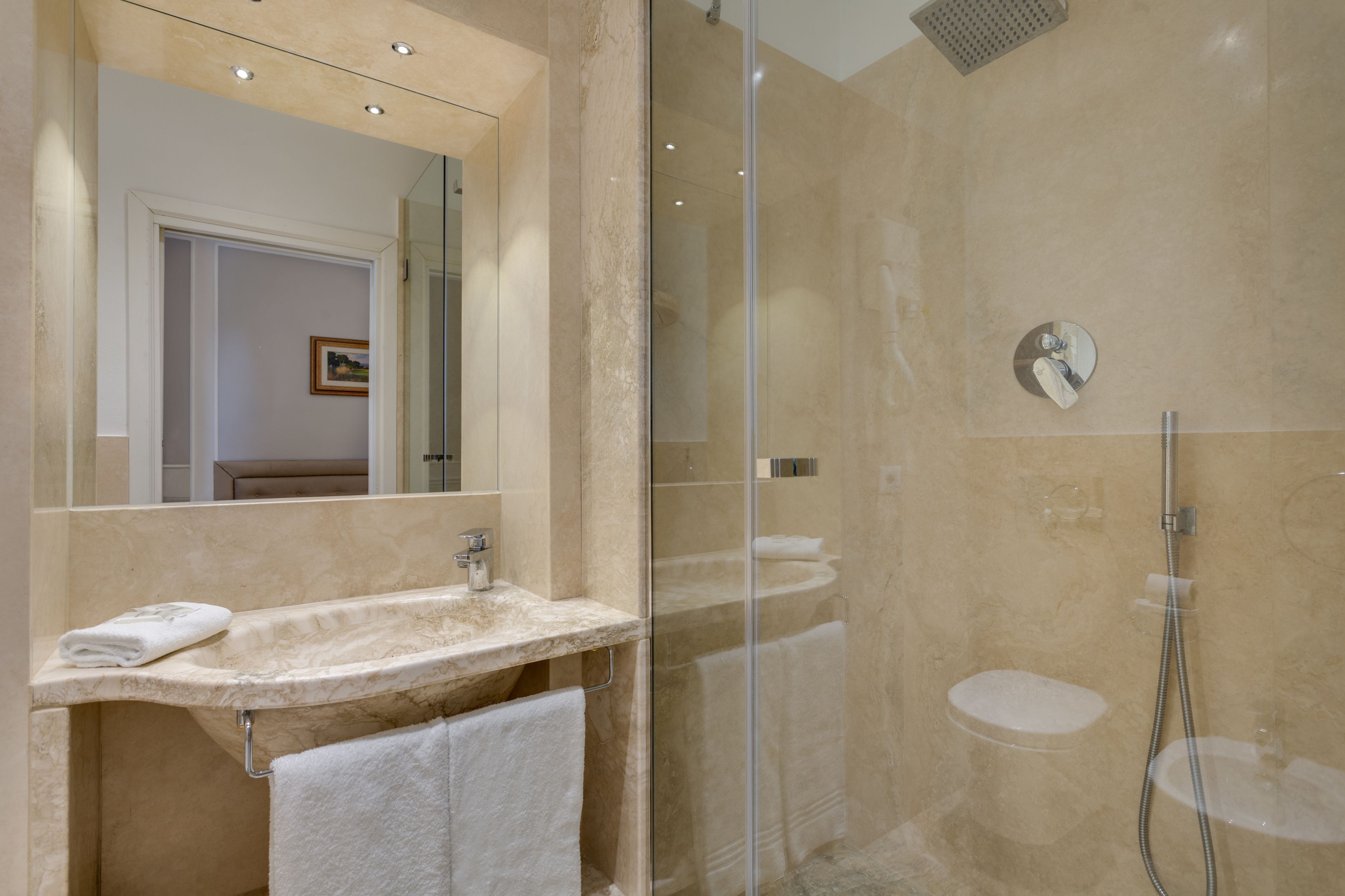 Une salle de bain moderne avec une douche à parois de verre, un lavabo avec un miroir et un porte-serviettes.