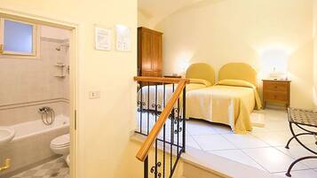 A bedroom with a bed, nightstand, and a wooden staircase.