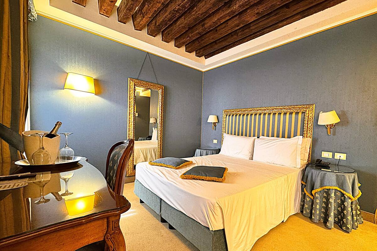 A hotel room with a bed, bedside tables, a mirror, and a desk with a chair.