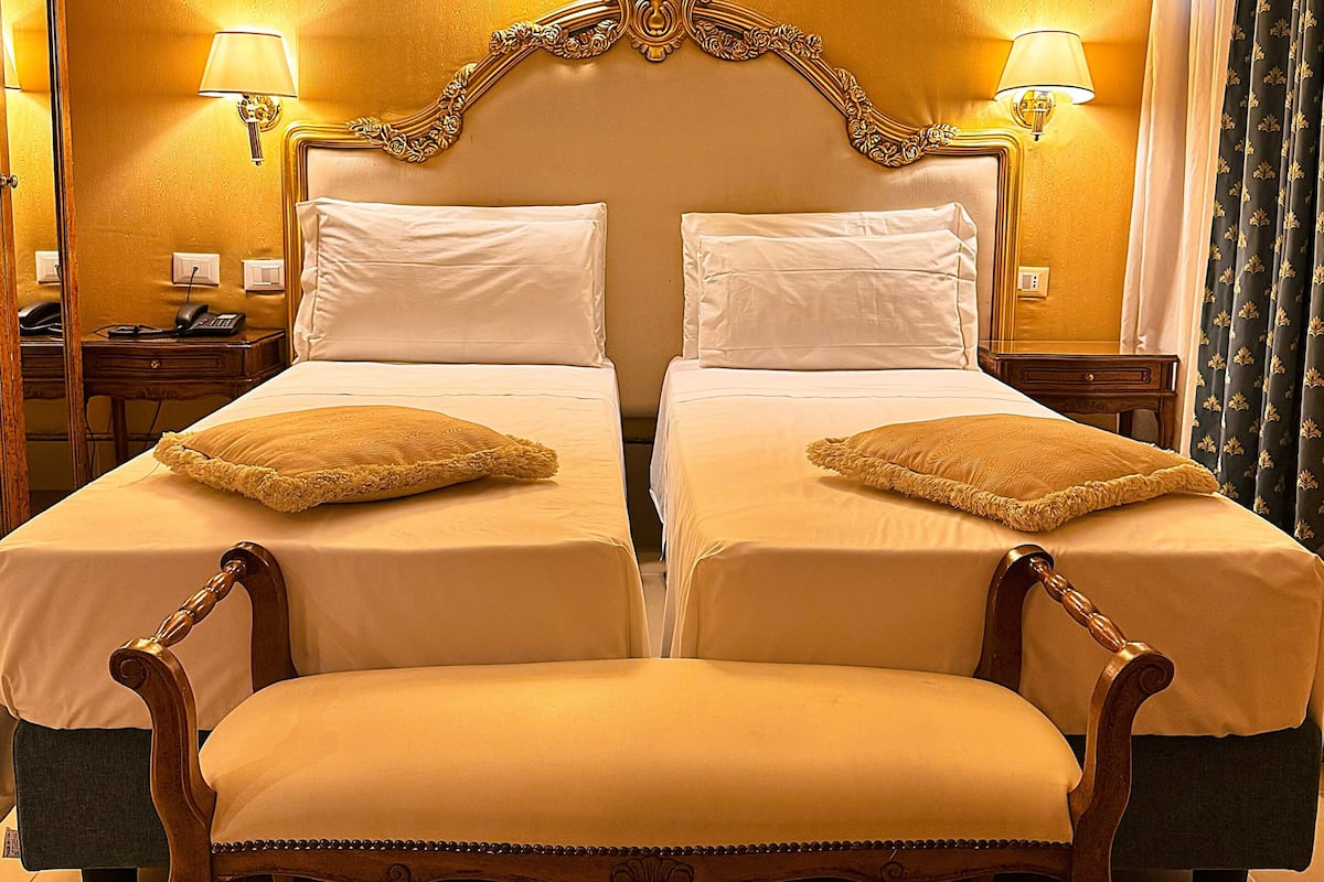A double bed with a wooden headboard and two bedside tables, each with a lamp.