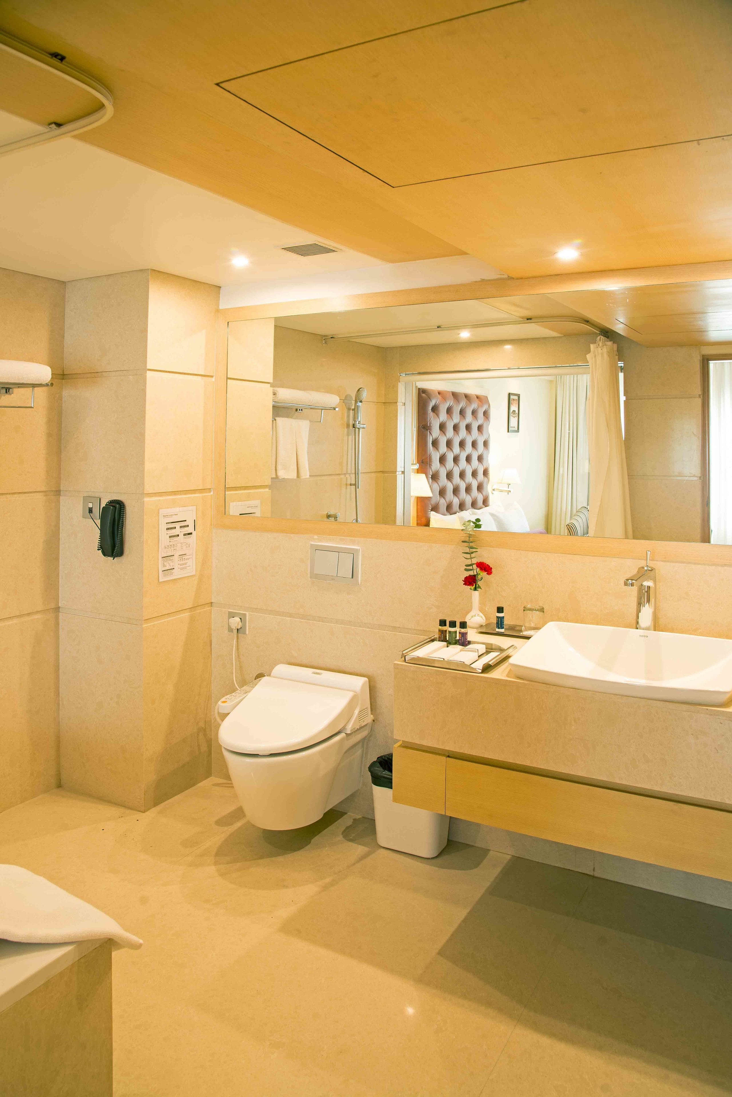 Un baño moderno con un espejo grande, dos lavamanos, un inodoro y una zona de ducha.