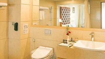 Un baño moderno con un espejo grande, dos lavamanos, un inodoro y una zona de ducha.