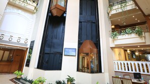 A hotel lobby with a central staircase, multiple balconies with plants, and a reception desk. - The Chancery Hotel (Bengaluru)