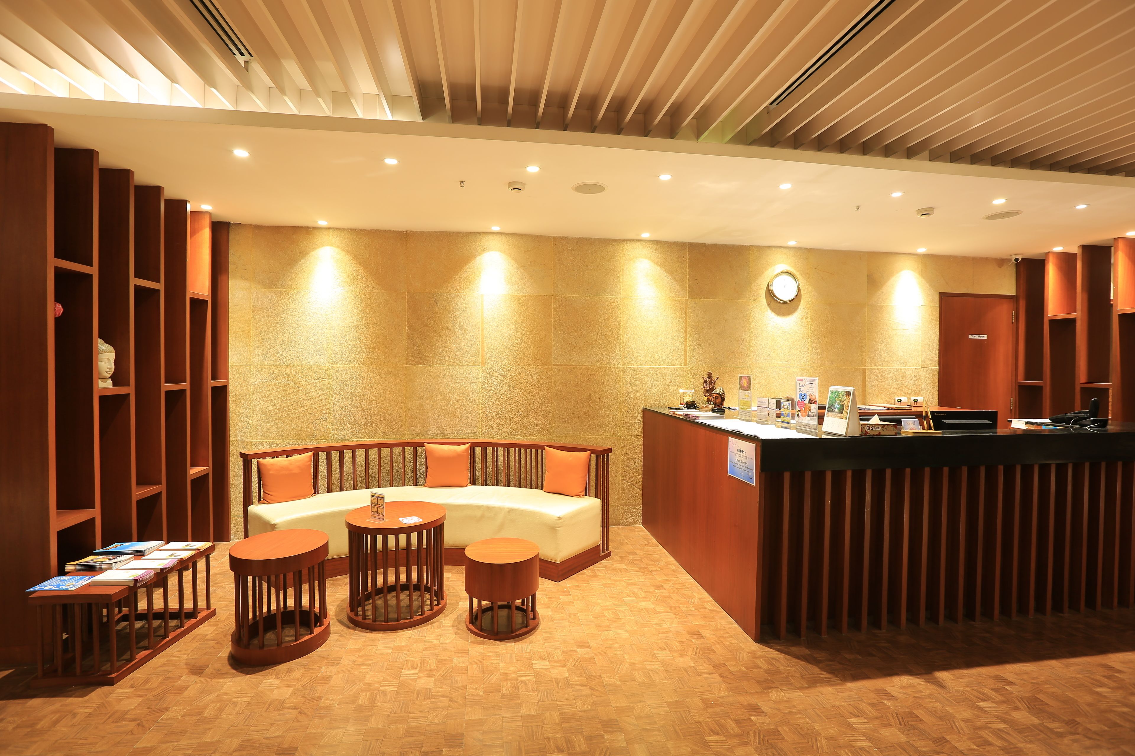 A reception area with a wooden reception desk, a sofa, and two round tables.