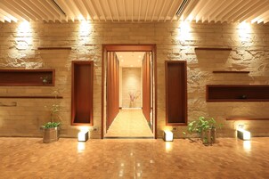 A hallway with a stone wall, wooden doors, and potted plants.