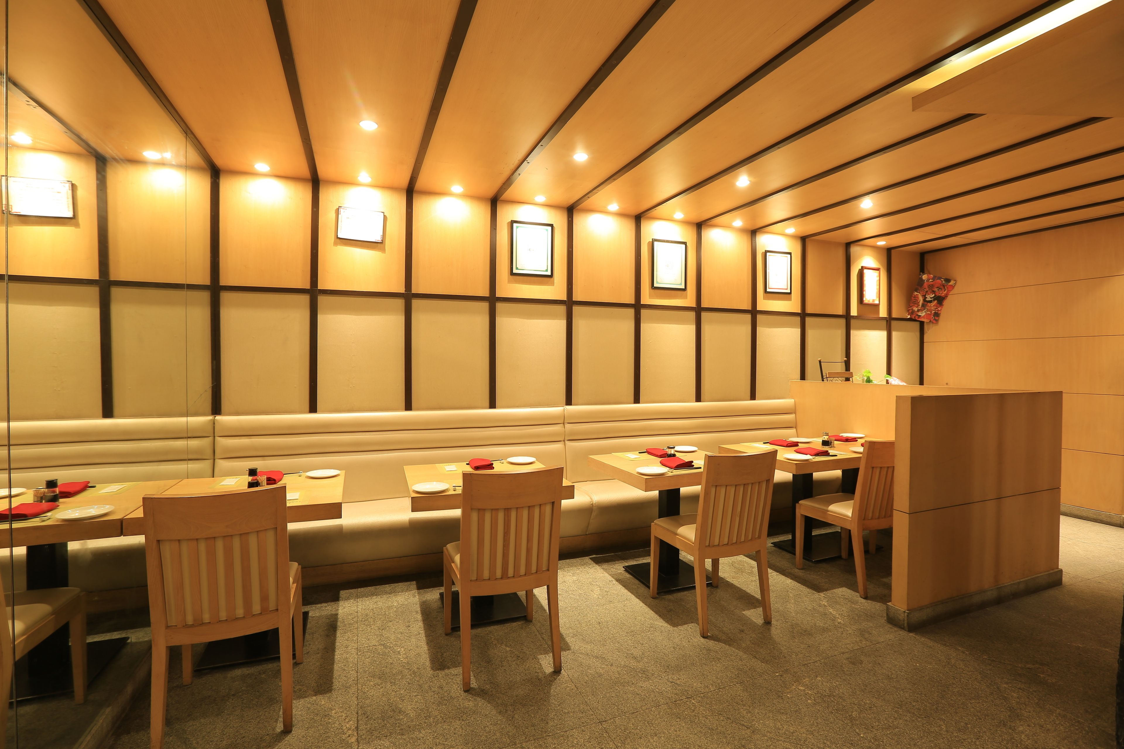 A restaurant with booths and tables, wooden chairs, and a counter.