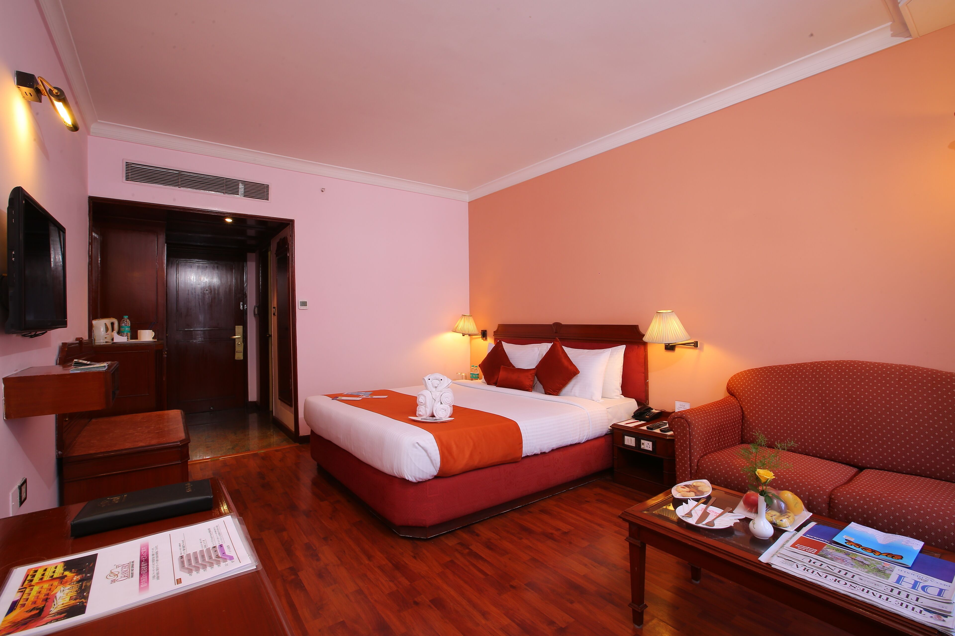 A hotel room with a bed, a sofa, a desk, and a nightstand.