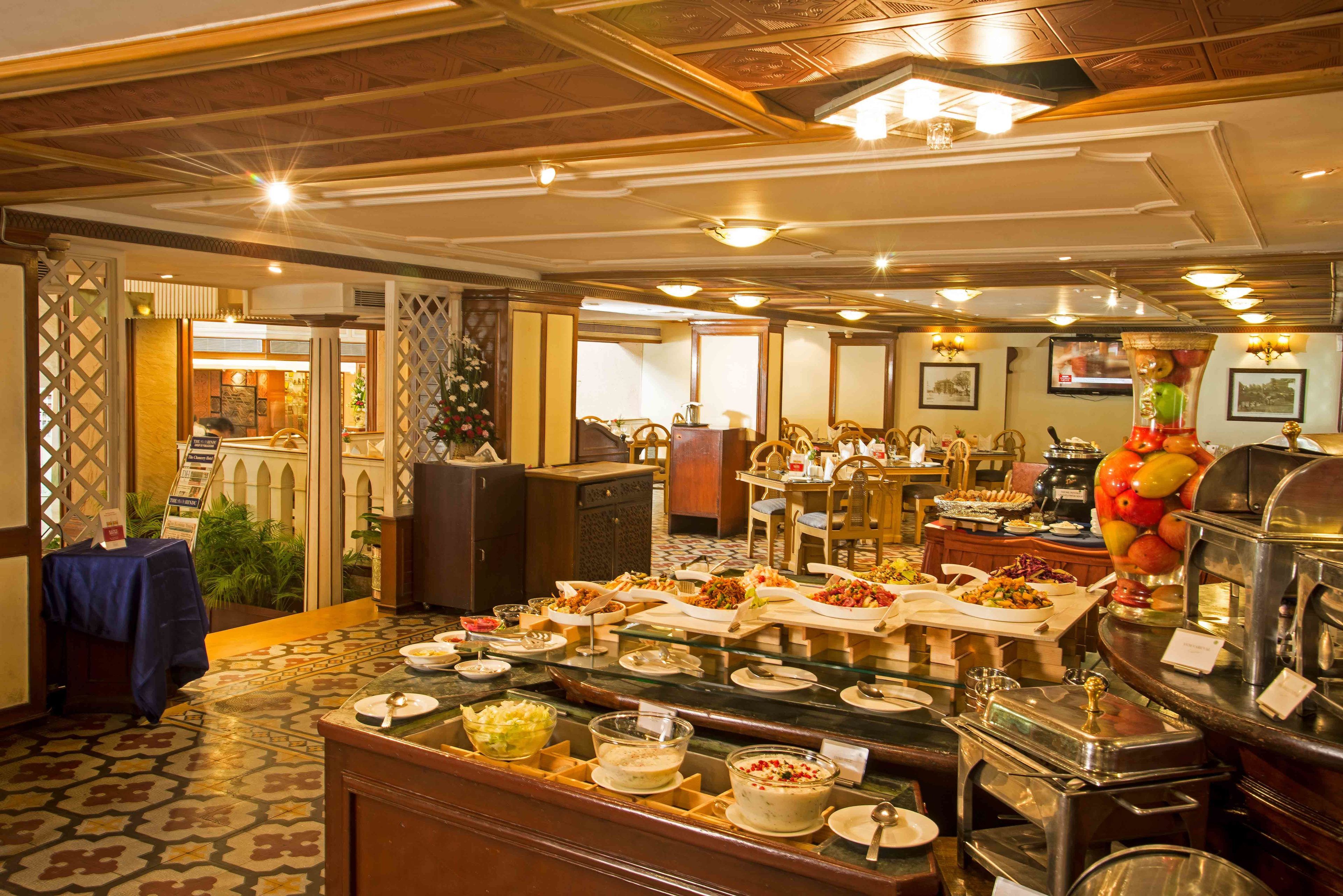 Montaje tipo buffet con diversos alimentos y una zona de estar con mesas y sillas.