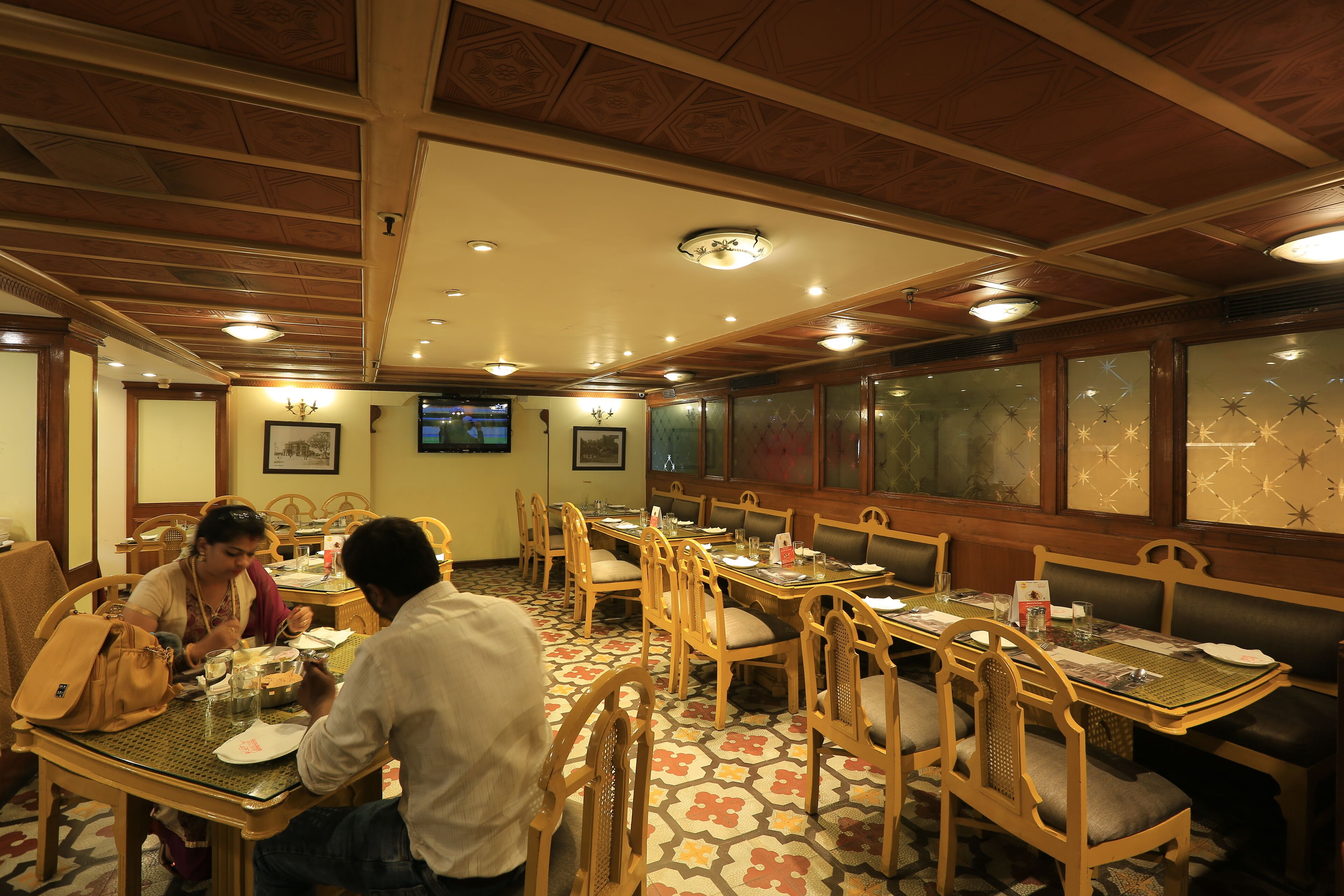 A restaurant with wooden furniture and patterned floor tiles.