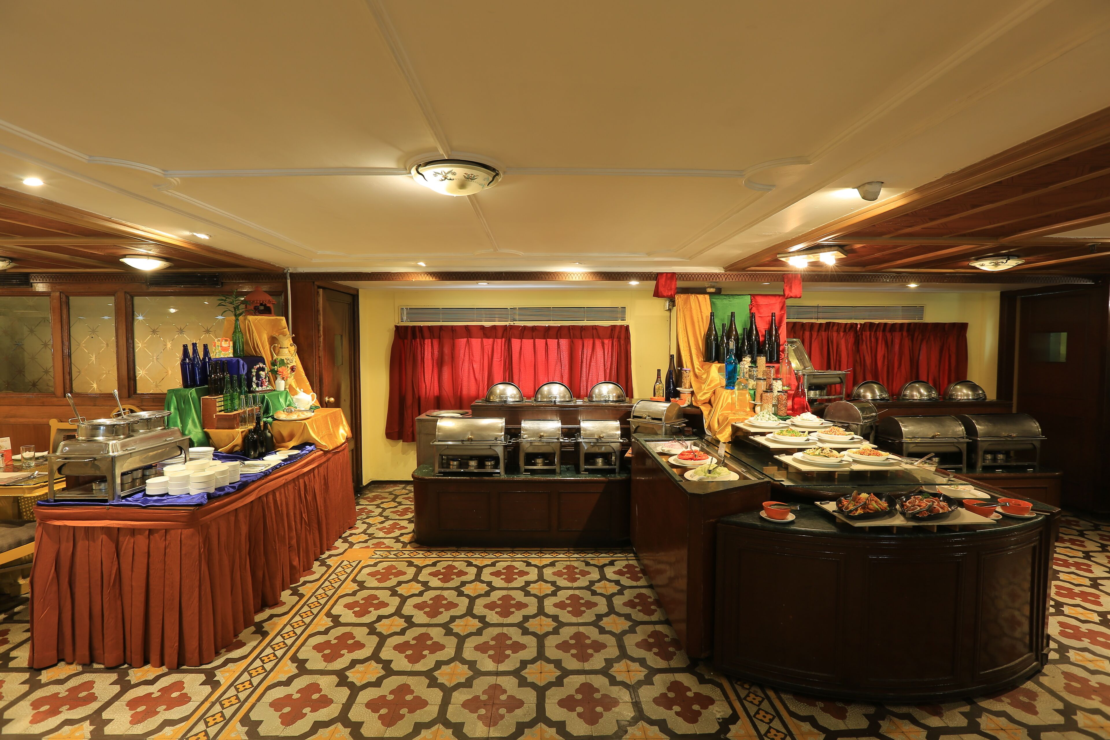 A buffet setup with multiple food stations, a patterned carpet, and a wooden ceiling.