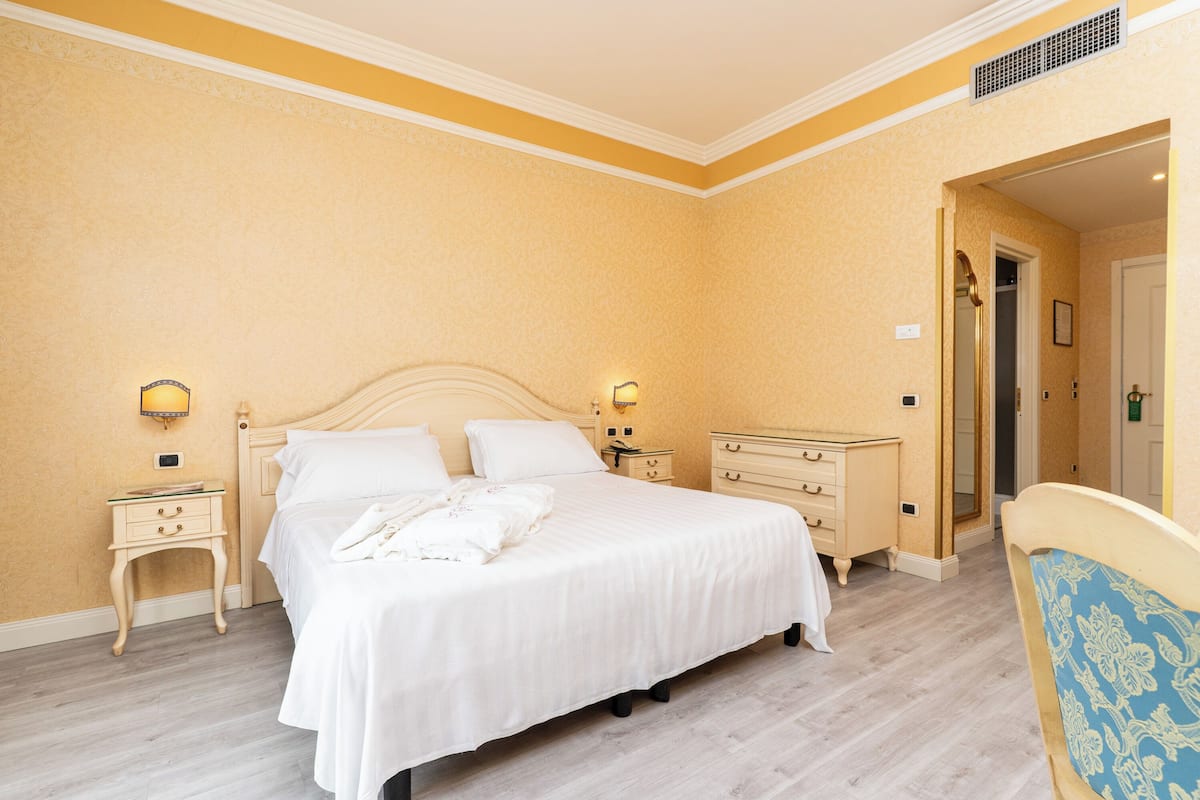 Un dormitorio con cama, mesitas de noche, cómoda y una silla.