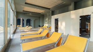 A row of yellow lounge chairs in a sunlit indoor area with large windows and a tiled floor. - Hotel Terme Helvetia (Abano Terme)