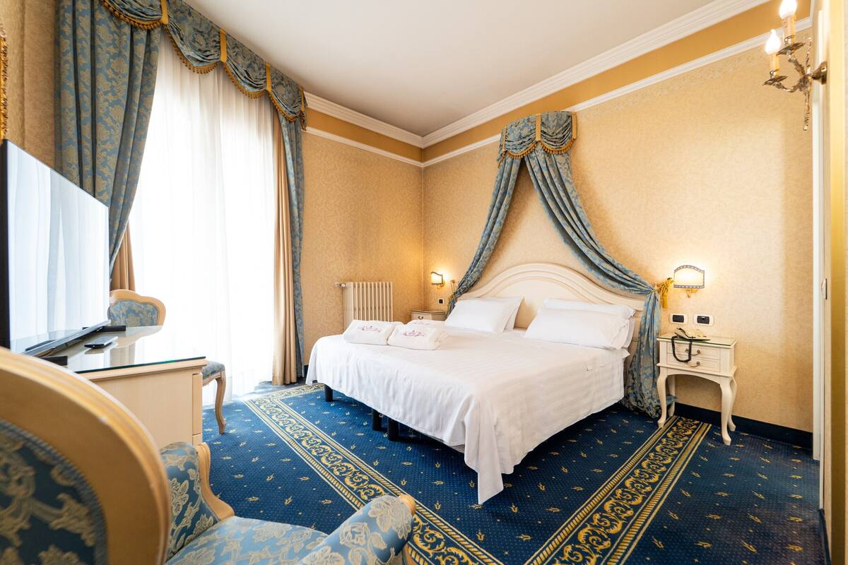 Una habitación de hotel con cama, escritorio, silla y mesita de noche.