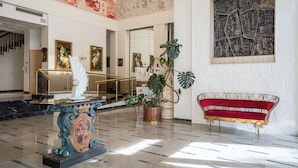 A lobby with a marble floor, a statue, a red sofa, and a large painting. - Hotel Terme Helvetia (Abano Terme)