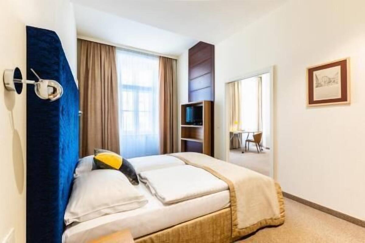 A hotel room with a bed, a TV, a desk, and a chair.