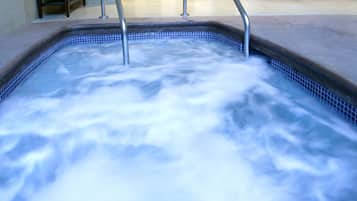 Relax in a spacious hot tub with a metal ladder for easy access, surrounded by a seating area with a bench and a potted plant.