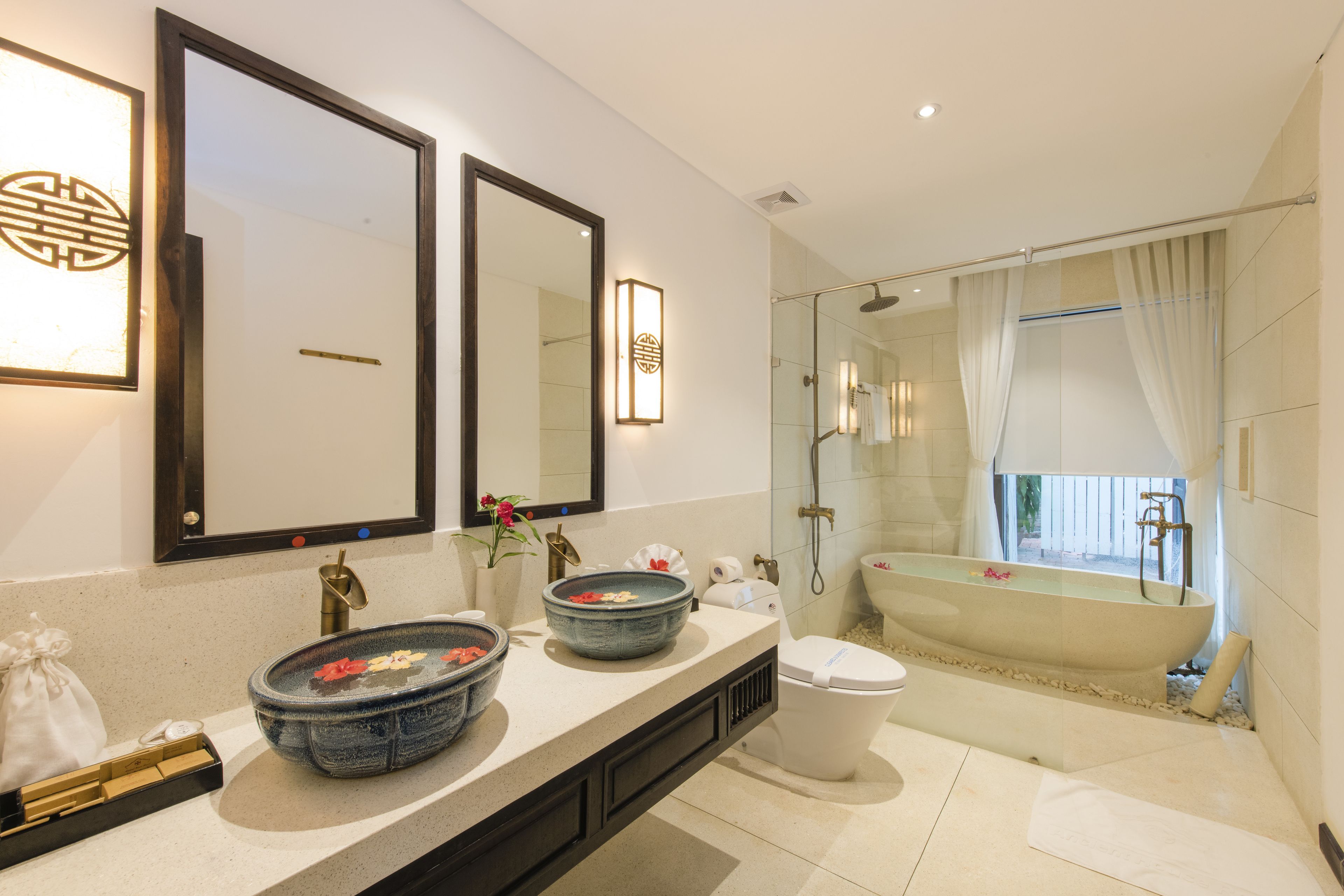 A modern bathroom with two large mirrors, a freestanding bathtub, and a glass-enclosed shower area.