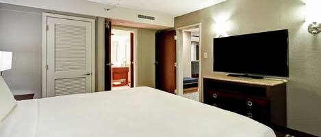 A hotel room with a bed, a television on a dresser, and a door leading to a bathroom.