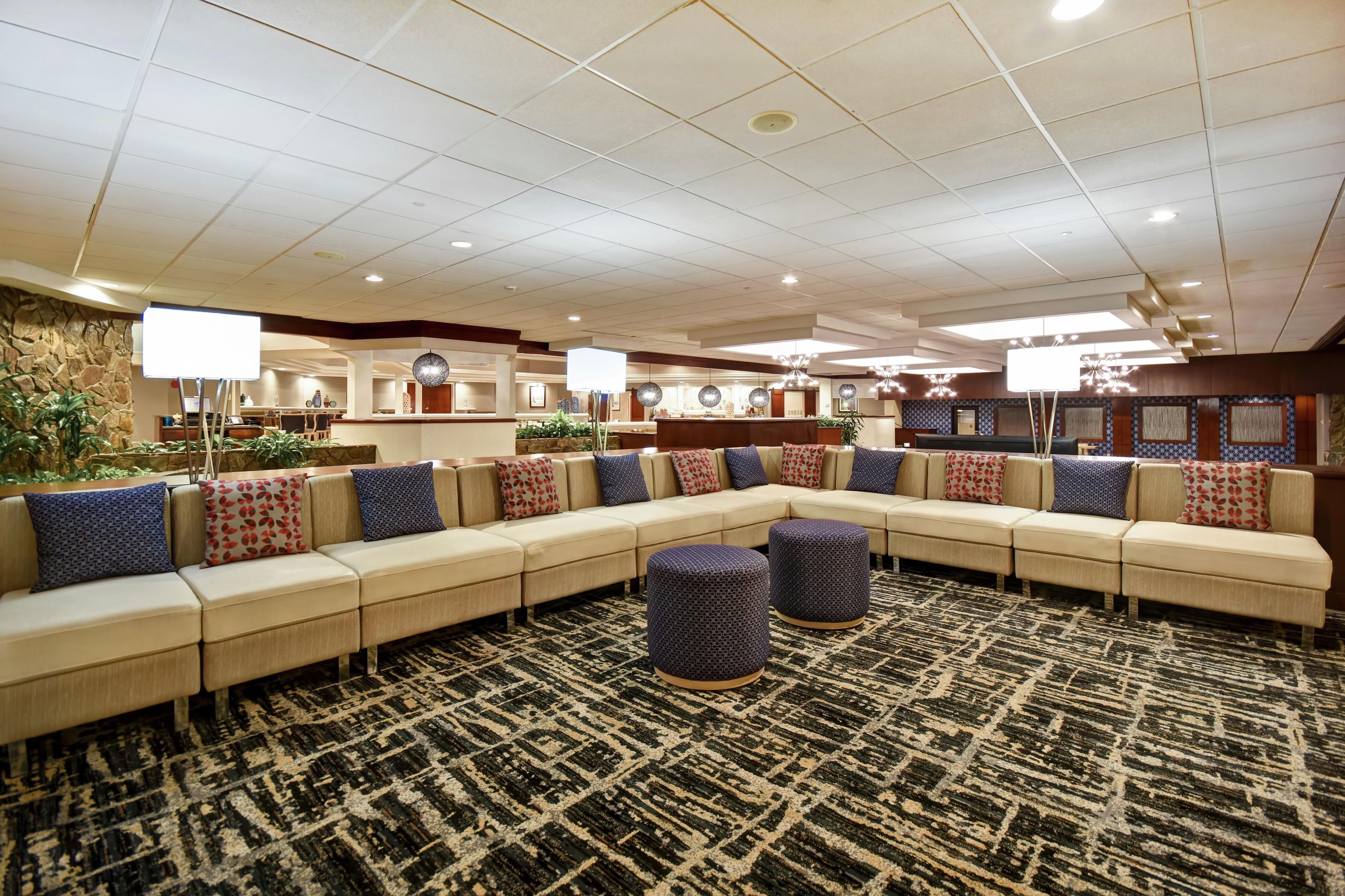 A hotel lobby with a large sectional sofa, a patterned carpet, and a stone accent wall.