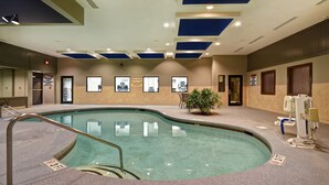 Una piscina interior con un letrero que indica una profundidad de 3 pies, una silla de salvavidas y un letrero de no buceo.