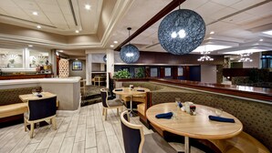 Un restaurante moderno con mesas redondas y cabinas, una zona de bar y un techo decorativo.