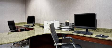 Un bureau d’hôtel équipé de deux bureaux, de chaises, d’ordinateurs et d’une imprimante.