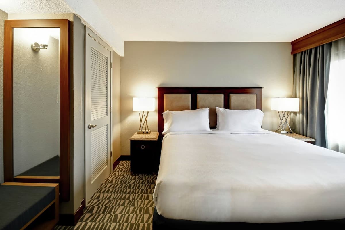 Ein Hotelzimmer mit einem großen Bett, zwei Nachttischlampen, einem Nachttisch, einer Tür und einem gemusterten Teppich.
