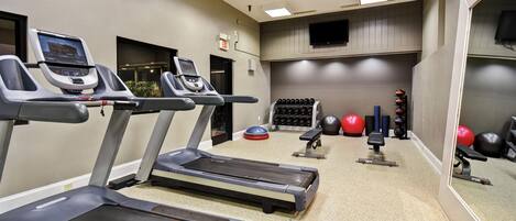 A gym with treadmills, weights, and exercise balls.