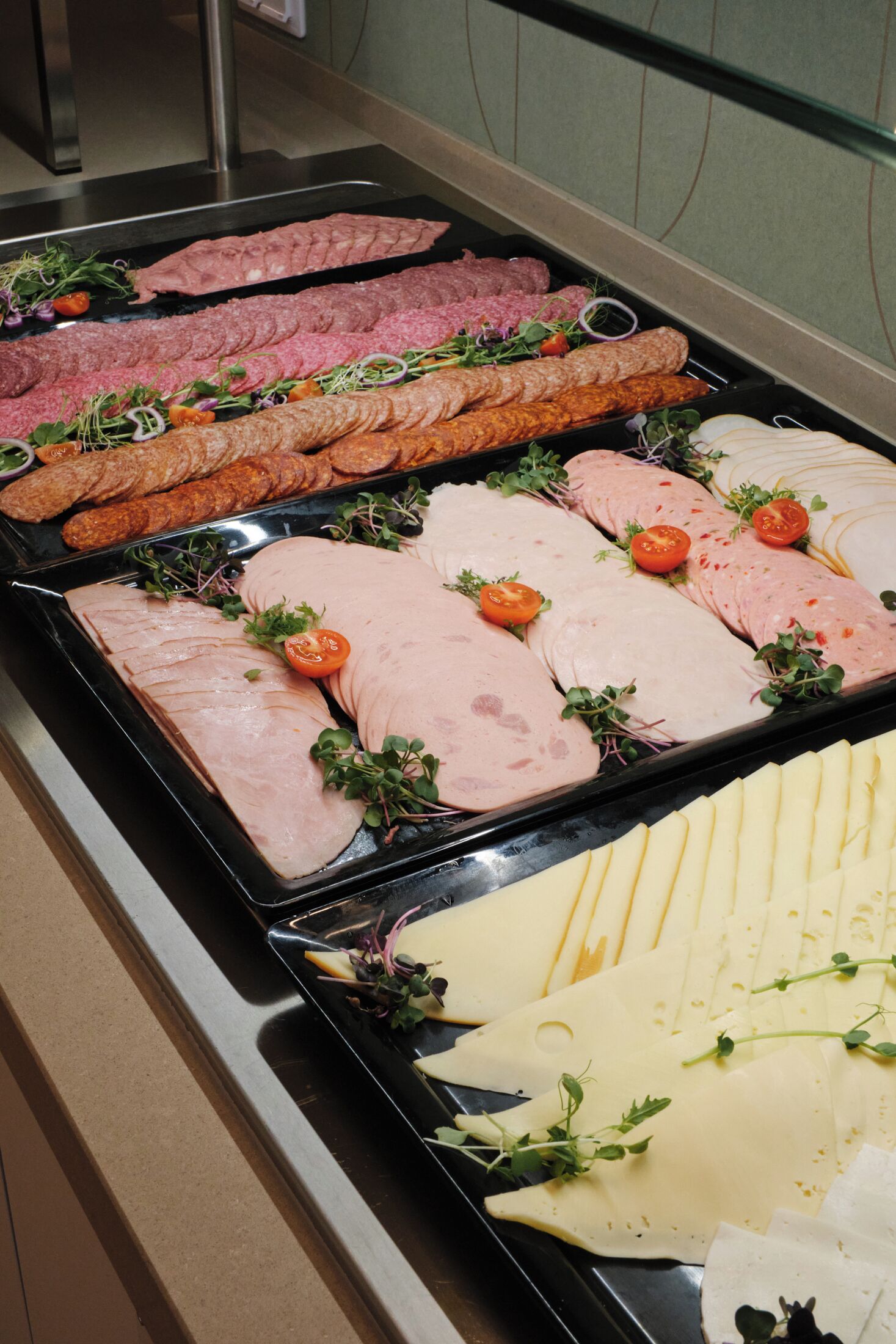 A buffet with various meats and cheeses.