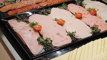 A buffet with various meats and cheeses.