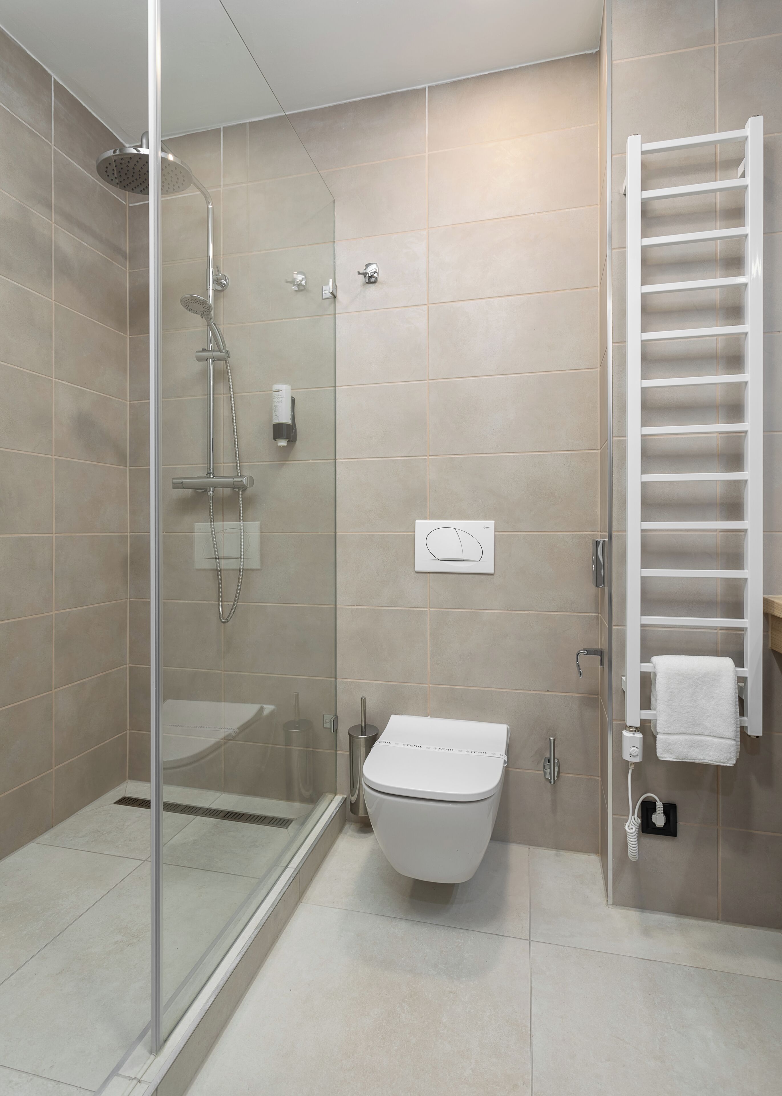 A modern bathroom with a glass-enclosed shower, a toilet, and a towel rack.