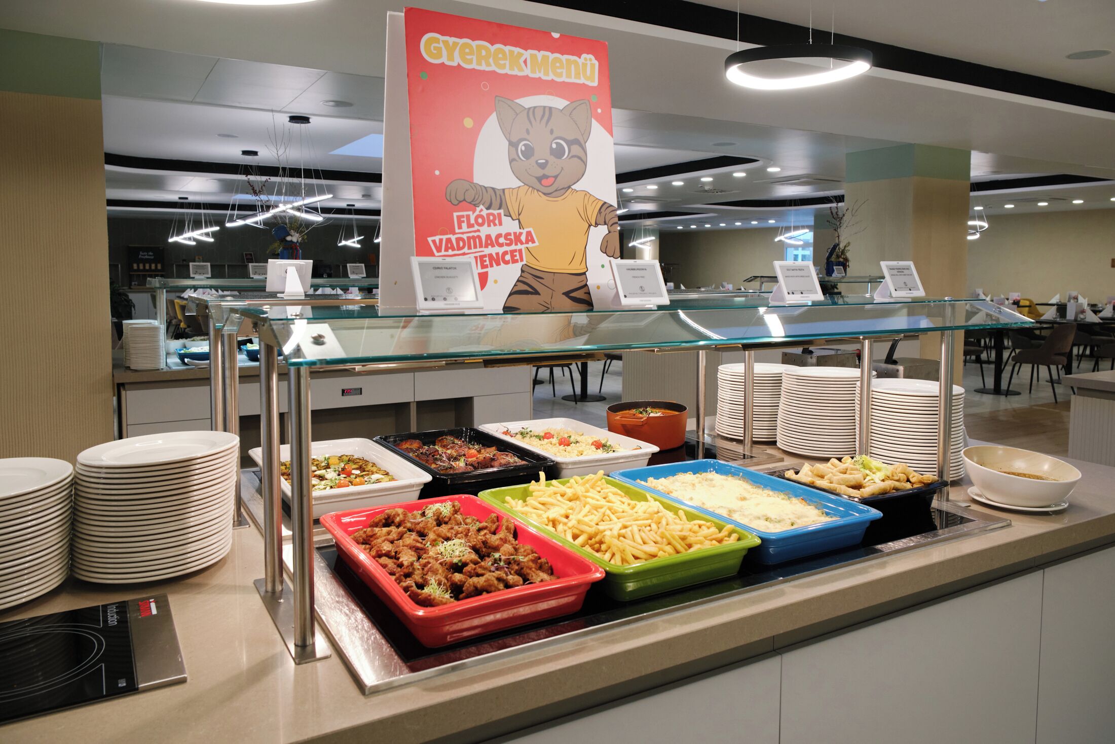 A buffet area with various food dishes, a glass display case, and a sign with a cat illustration.