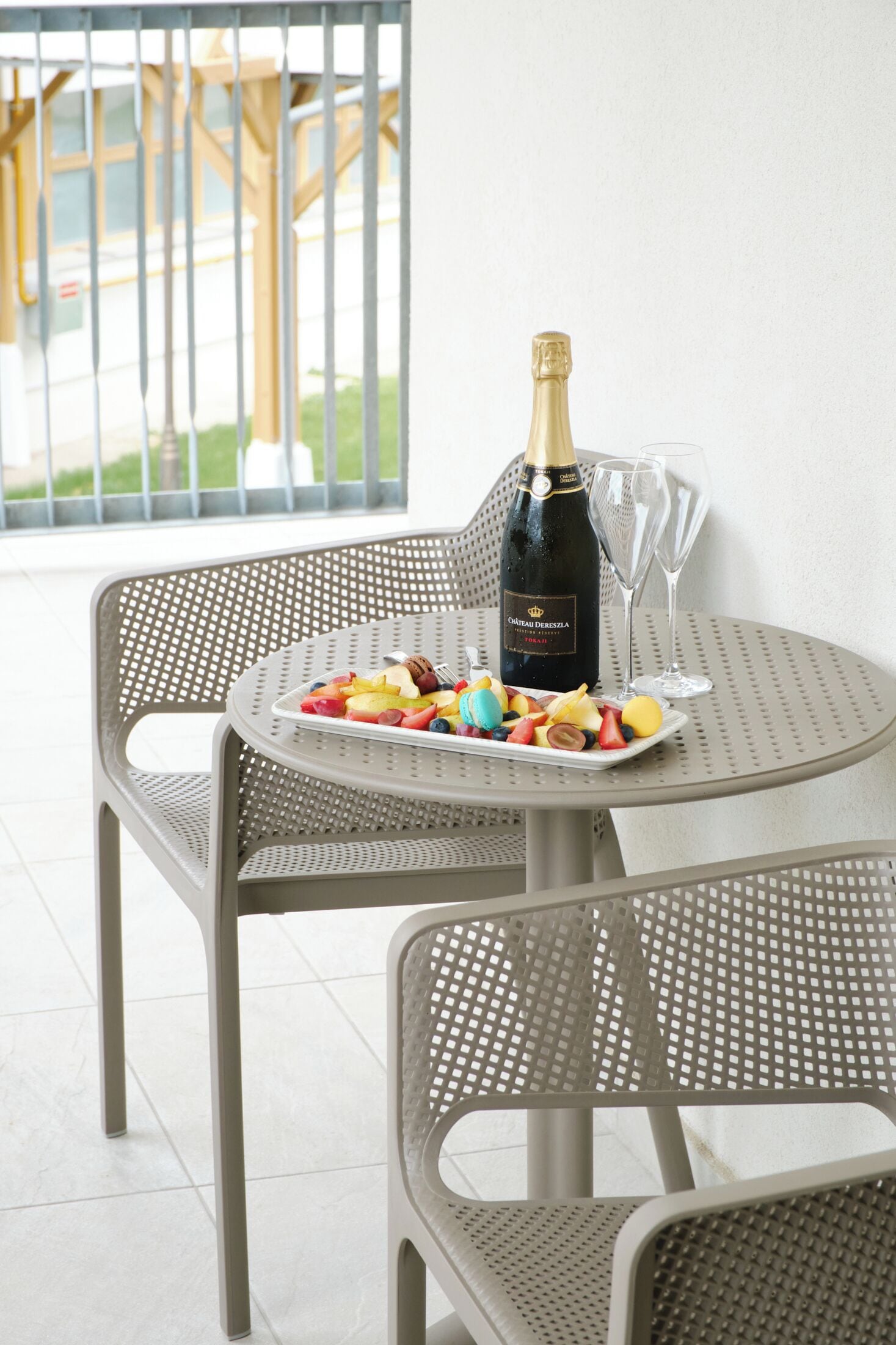 Une table avec une bouteille de champagne, deux verres et une assiette de fruits.