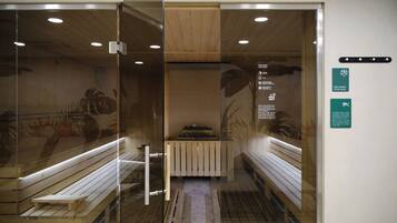 Un cuarto de sauna con bancos, puerta de vidrio, suelo de madera y luces en el techo.