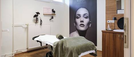 A clinical setting with a treatment bed, a poster, a wooden cabinet, and a radiator.