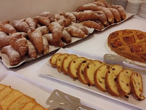 Una mesa de buffet con diversos pasteles, incluyendo croissants y una tarta.