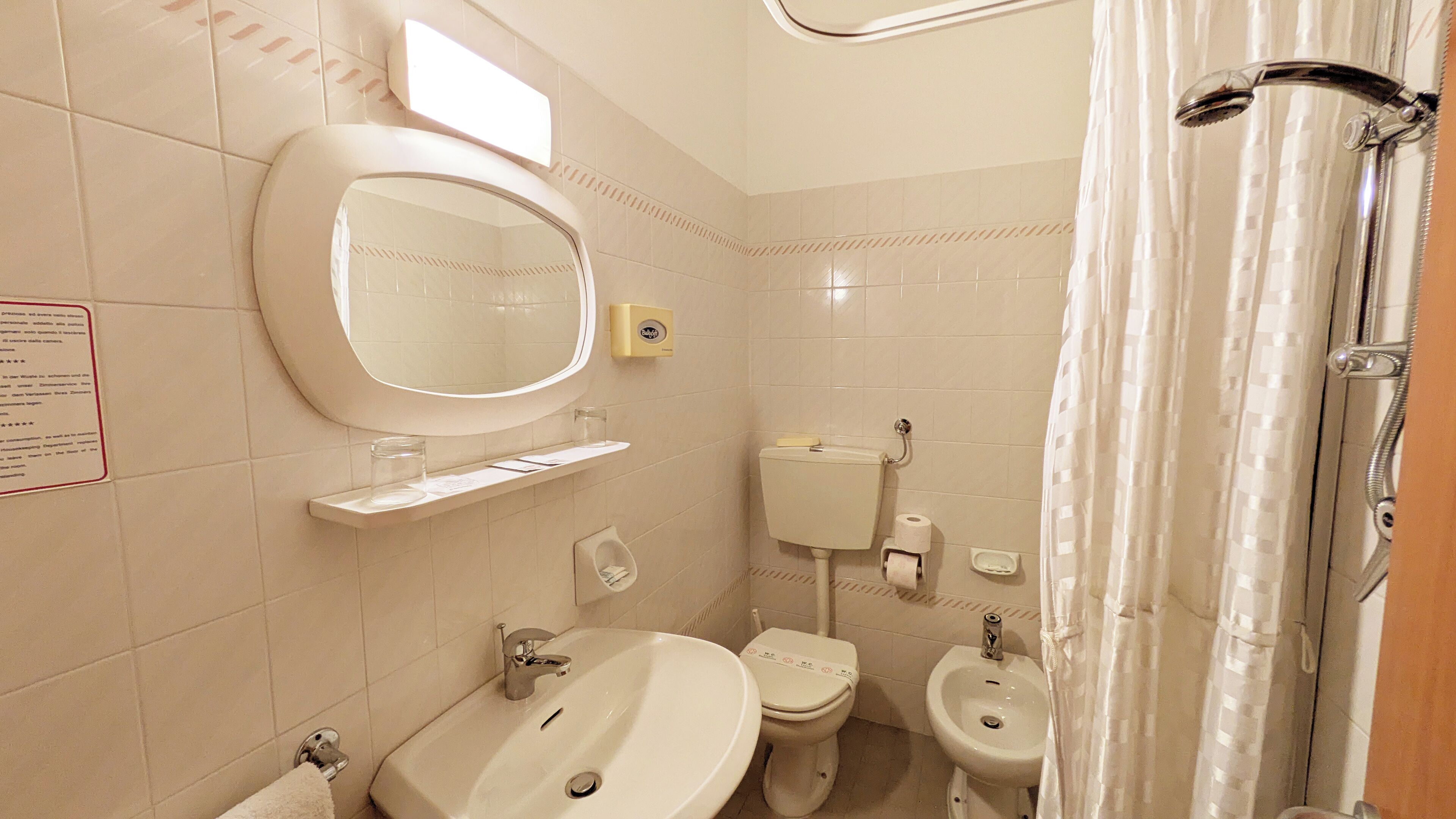 A bathroom with a sink, toilet, bidet, and shower.