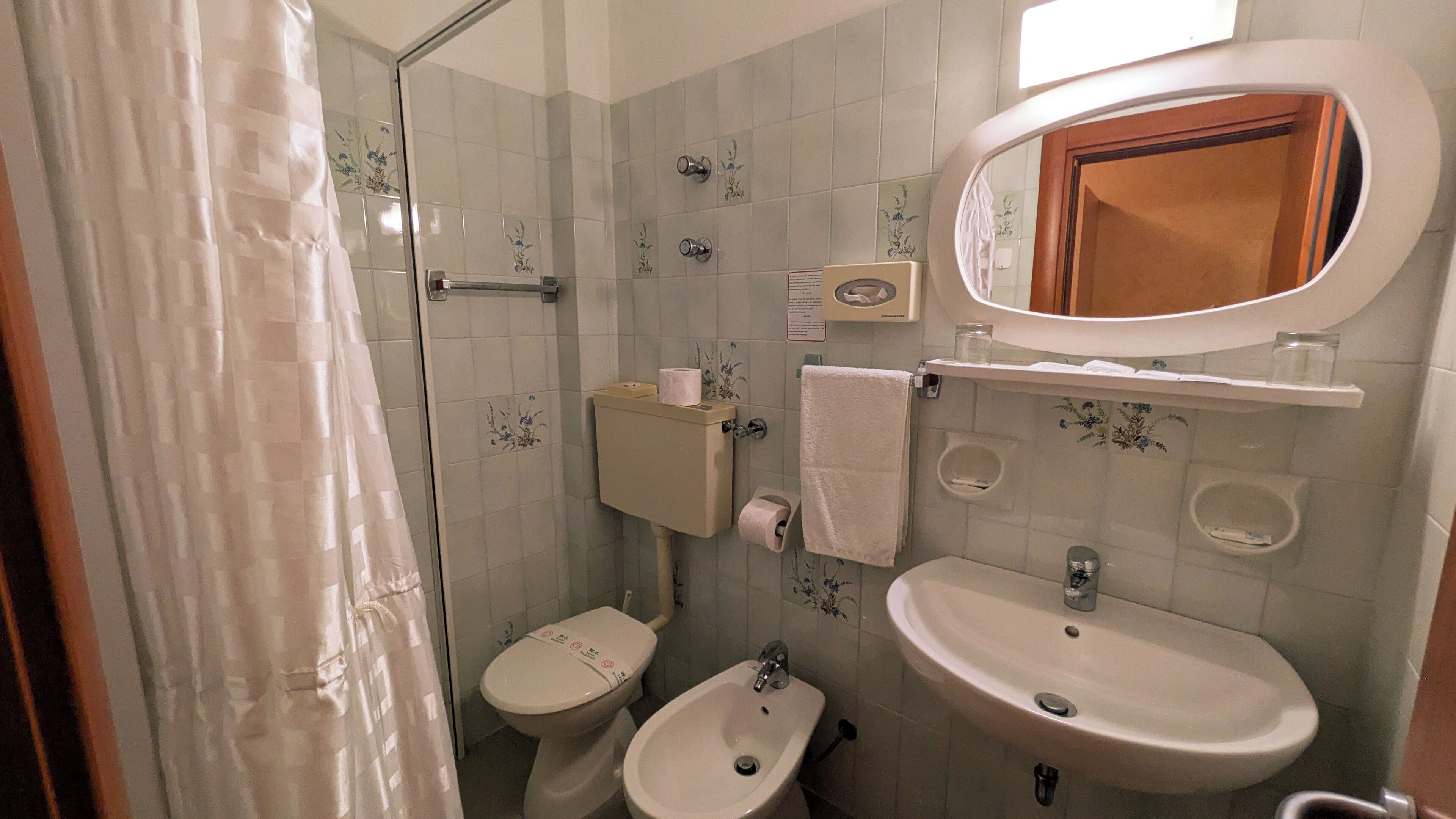 Une salle de bain équipée d’une douche, de toilettes, d’un bidet et d’un lavabo.