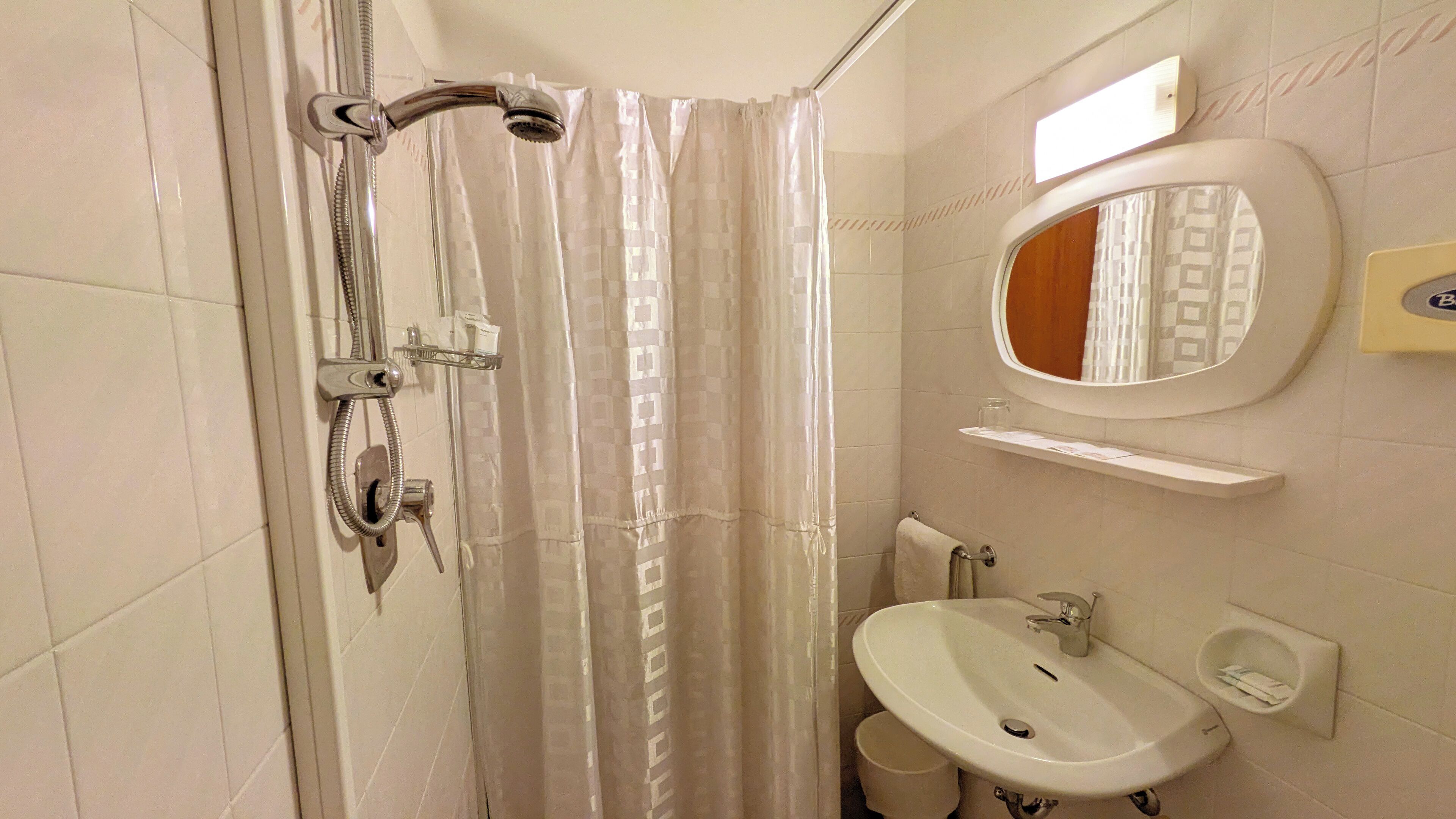 Une salle de bain équipée d’une douche, d’un lavabo, d’un miroir et d’un porte-serviettes.