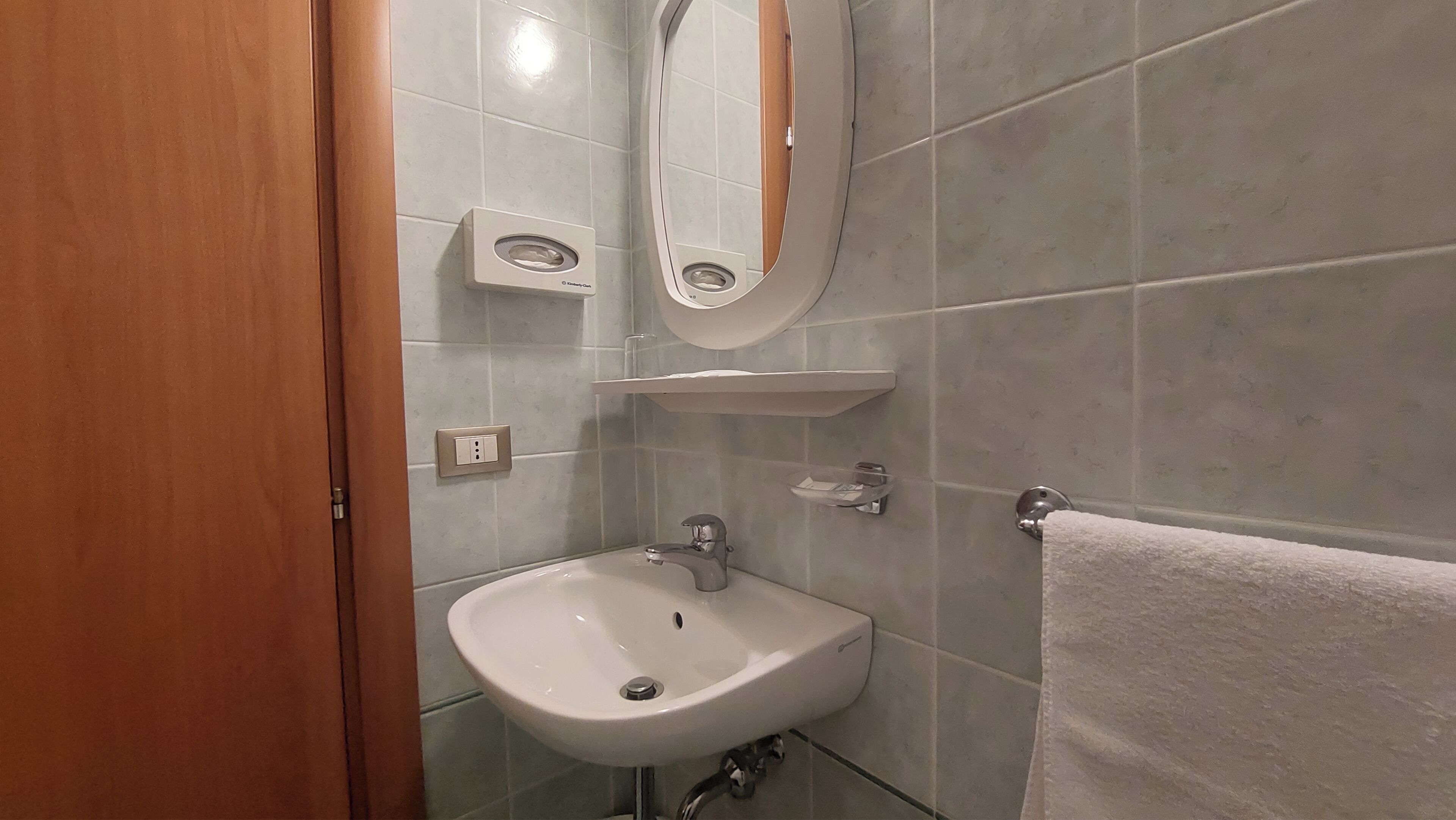A bathroom with a white sink, a mirror, and a towel rack.