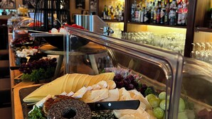 A buffet with various cheeses, fruits, and a selection of bottles in the background. - Hotel-Restaurant Amadeus (Isernhagen)