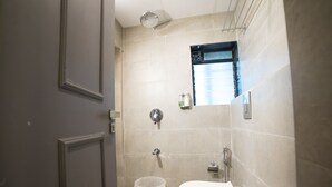 A bathroom with a toilet, a shower, and a small window. - Hotel Highway Residency (Mumbai)