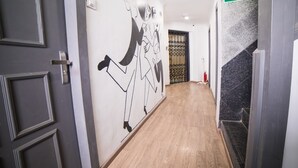A hallway with a black door, a wall mural, a fire exit sign, and a staircase. - Hotel Highway Residency (Mumbai)