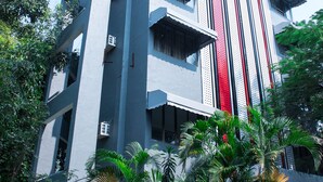 A multi-story building with balconies, large windows, and a red vertical stripe. - Hotel Highway Residency (Mumbai)