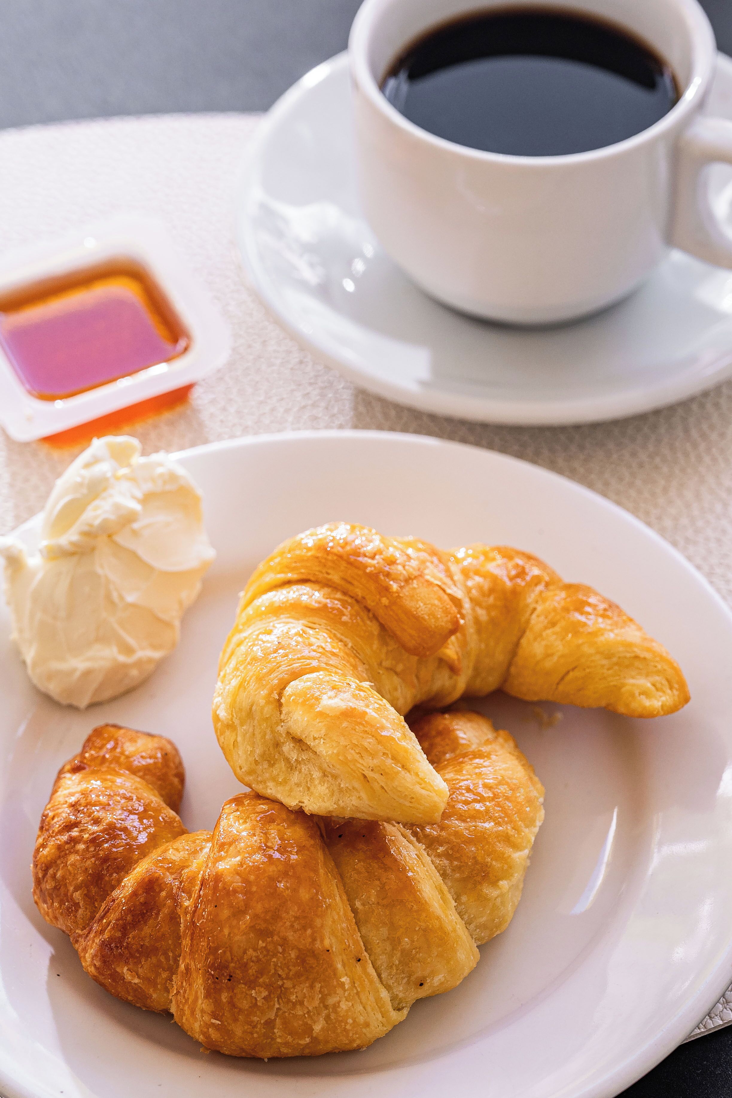 A plate with croissants and a cup of coffee on a table.